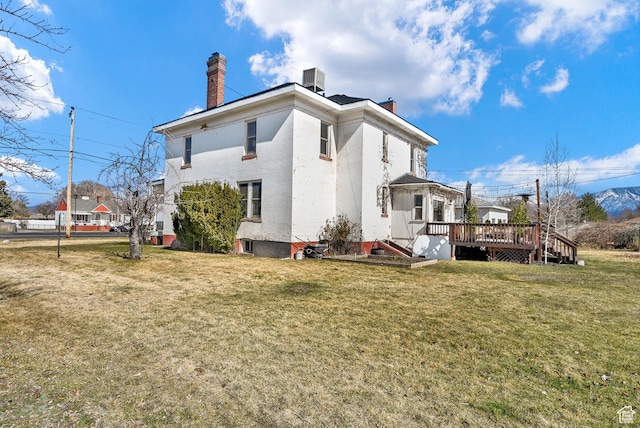 back of house featuring central air condition unit, a chimney, a deck, and a yard