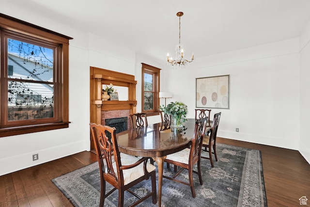 dining room with dark wood-style flooring, baseboards, an inviting chandelier, and a fireplace
