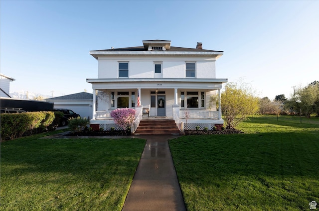 american foursquare style home with a front yard, a porch, and stucco siding