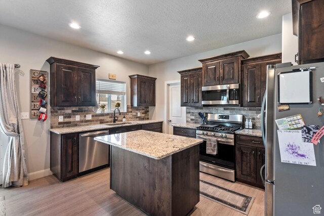 1933 E Handcart Ln N, Spanish Fork, UT 84660 - kitchen featuring a center island, appliances with stainless steel finishes, dark brown cabinetry, a sink, and light wood-type flooring