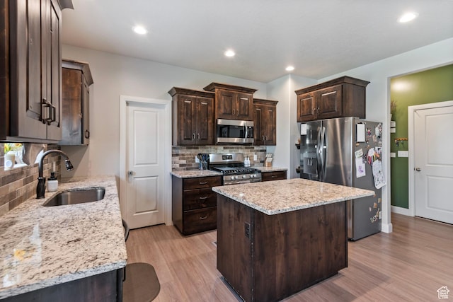 1933 E Handcart Ln N, Spanish Fork, UT 84660 - kitchen with dark brown cabinetry, light wood-style flooring, a kitchen island, appliances with stainless steel finishes, and a sink