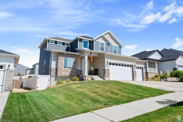 craftsman-style home with concrete driveway, stone siding, fence, a front lawn, and board and batten siding