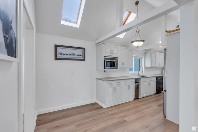 kitchen featuring light countertops, stainless steel microwave, a skylight, and a sink