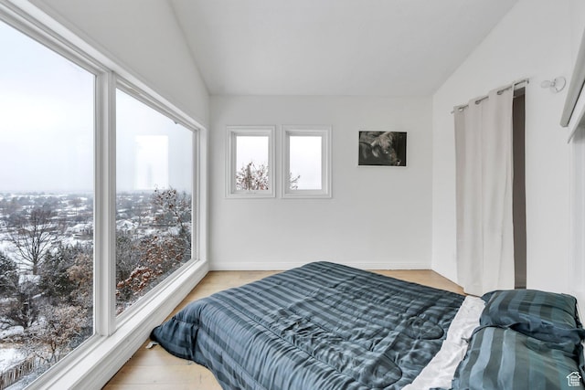 bedroom featuring lofted ceiling, light wood-type flooring, and baseboards