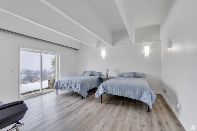 bedroom featuring access to exterior, baseboards, beam ceiling, and wood finished floors