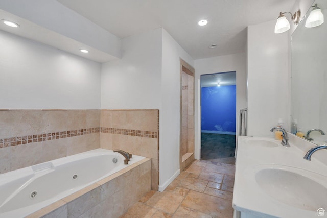 bathroom with stone tile flooring, double vanity, a tub with jets, and a sink