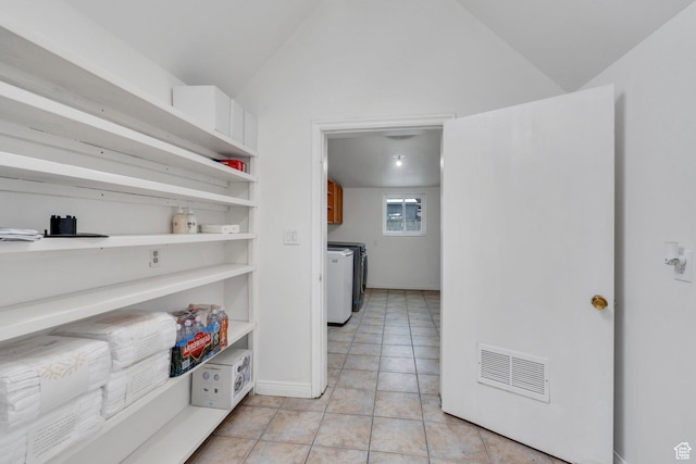 interior space featuring open shelves, visible vents, light tile patterned flooring, vaulted ceiling, and washer and dryer