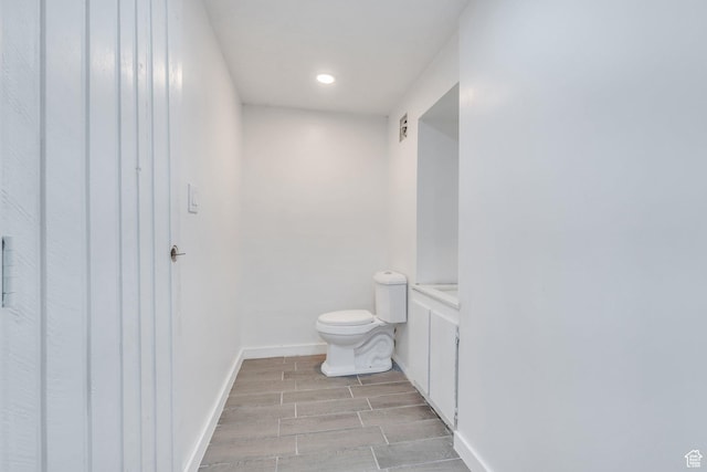 bathroom featuring wood tiled floor, baseboards, toilet, and recessed lighting