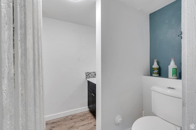 bathroom featuring toilet, baseboards, wood finished floors, and vanity