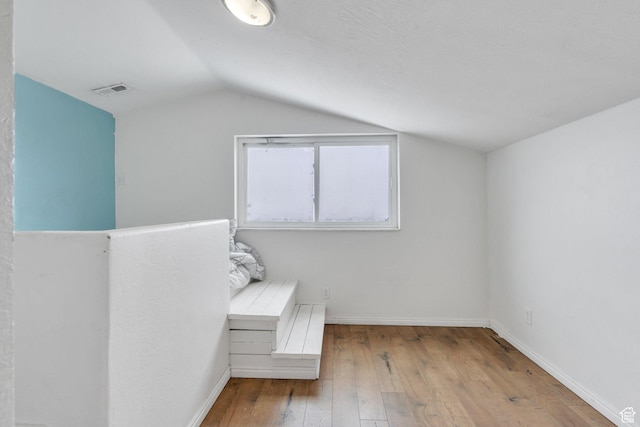 unfurnished bedroom with lofted ceiling, wood-type flooring, visible vents, and baseboards