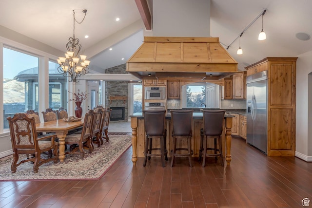 2008 N 3850 E, Eden, UT 84310 - dining space featuring an inviting chandelier, rail lighting, high vaulted ceiling, a stone fireplace, and dark wood-style floors