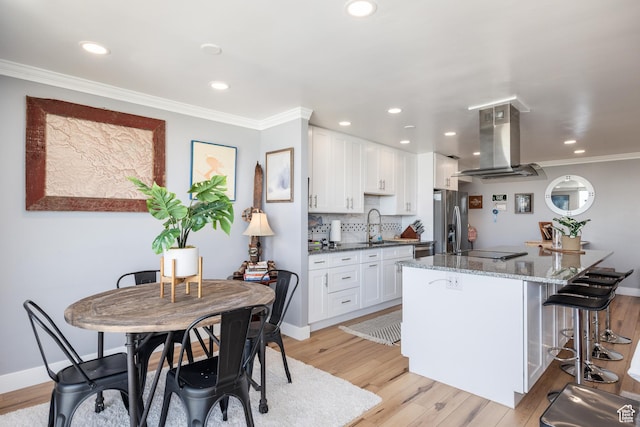 777 E S Temple S Unit 11F, Salt Lake City, UT 84102 - kitchen with island range hood, stainless steel appliances, a sink, light wood-style floors, and a kitchen breakfast bar