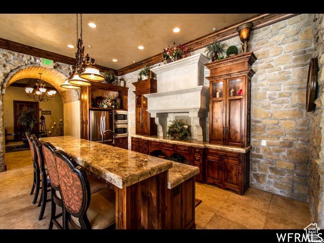 kitchen featuring arched walkways, hanging light fixtures, freestanding refrigerator, a chandelier, and a spacious island