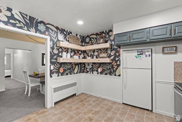 162 S 3 E, Preston, ID 83263 - interior space with a textured ceiling, wallpapered walls, radiator heating unit, blue cabinets, and freestanding refrigerator