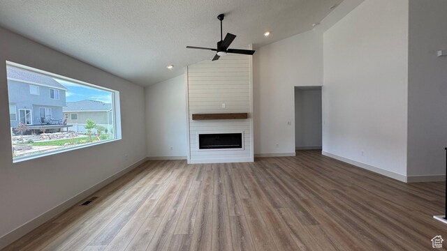 445 W 1910 N Unit 318, Tooele, UT 84074 - unfurnished living room featuring vaulted ceiling, a ceiling fan, a large fireplace, wood finished floors, and recessed lighting