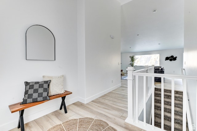 hall featuring baseboards, wood finished floors, and an upstairs landing