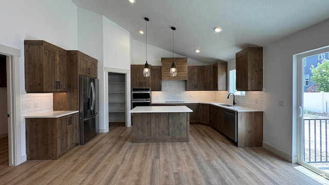 445 W 1910 N Unit 318, Tooele, UT 84074 - kitchen featuring appliances with stainless steel finishes, a center island, light wood-style floors, decorative backsplash, and vaulted ceiling