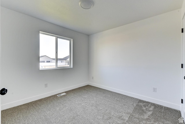 carpeted spare room featuring baseboards and visible vents