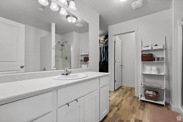 116 W Condor Rd N, Saratoga Springs, UT 84045 - full bathroom with visible vents, wood finished floors, a walk in closet, vanity, and a shower stall