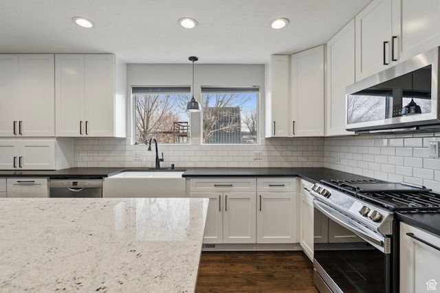 kitchen featuring dark wood-style floors, tasteful backsplash, appliances with stainless steel finishes, white cabinets, and a sink