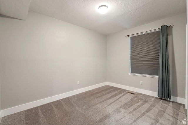 unfurnished room featuring a textured ceiling, carpet, visible vents, and baseboards