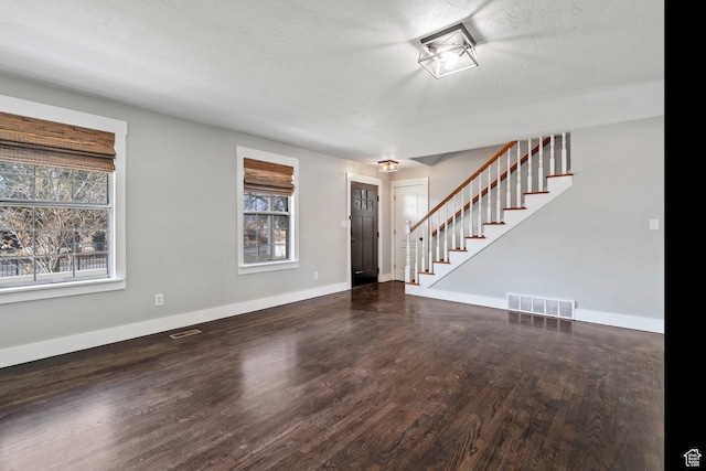 interior space with wood finished floors, visible vents, baseboards, and stairs