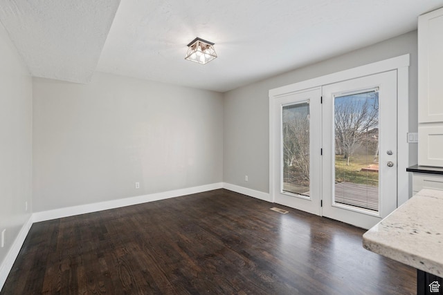 unfurnished dining area featuring baseboards and dark wood finished floors