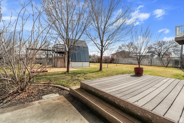 deck with a storage unit, fence, an outbuilding, and a yard