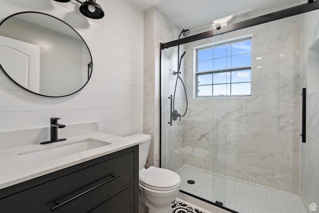 bathroom featuring a stall shower, vanity, toilet, and wooden walls