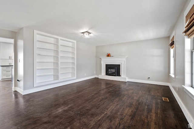 unfurnished living room featuring dark wood-style floors, a fireplace, and baseboards