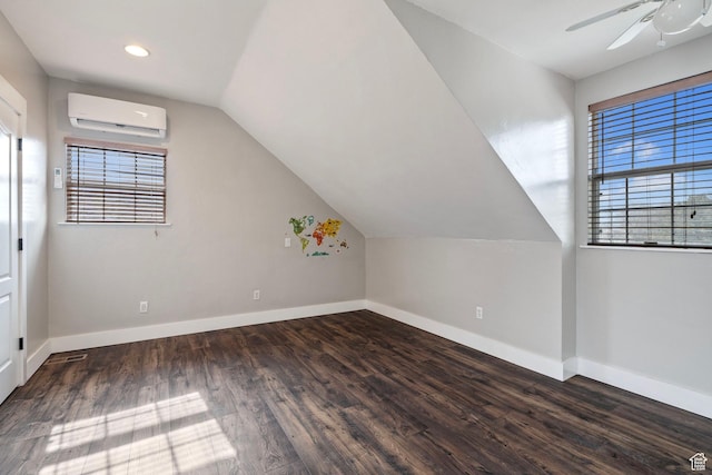 additional living space with lofted ceiling, an AC wall unit, baseboards, and dark wood-style flooring