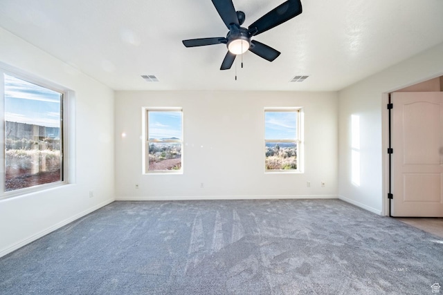 carpeted empty room featuring ceiling fan, visible vents, and baseboards