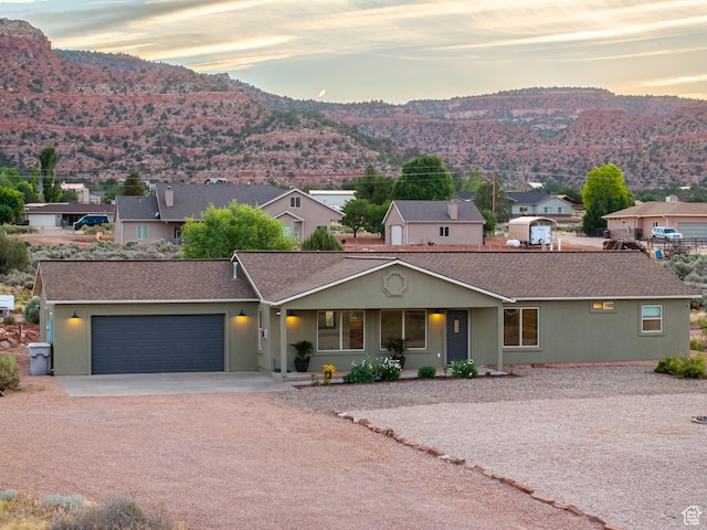 single story home featuring stucco siding, driveway, an attached garage, and a mountain view