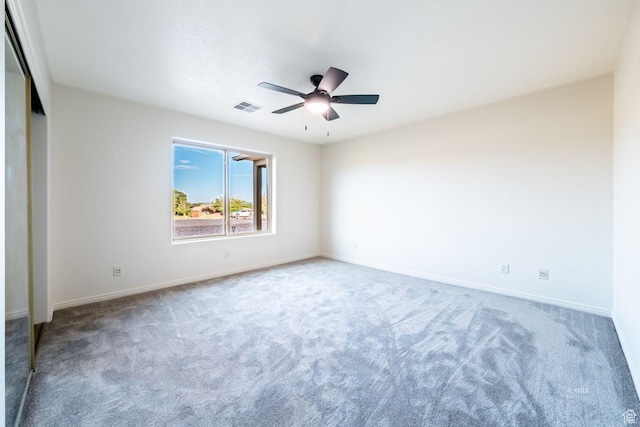 empty room featuring ceiling fan, carpet floors, visible vents, and baseboards