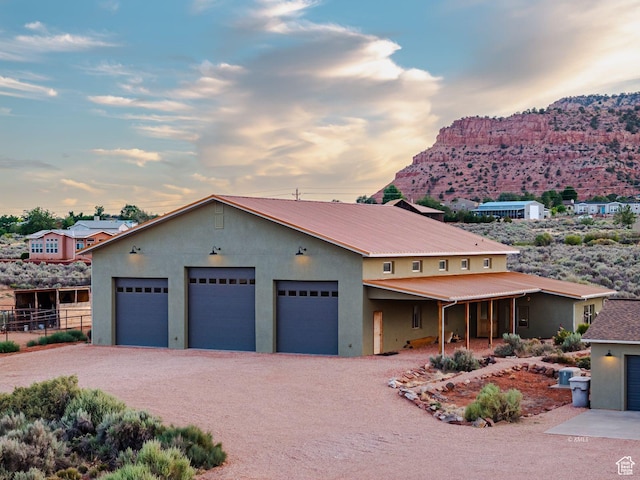 view of front of home with stucco siding, metal roof, fence, a garage, and driveway