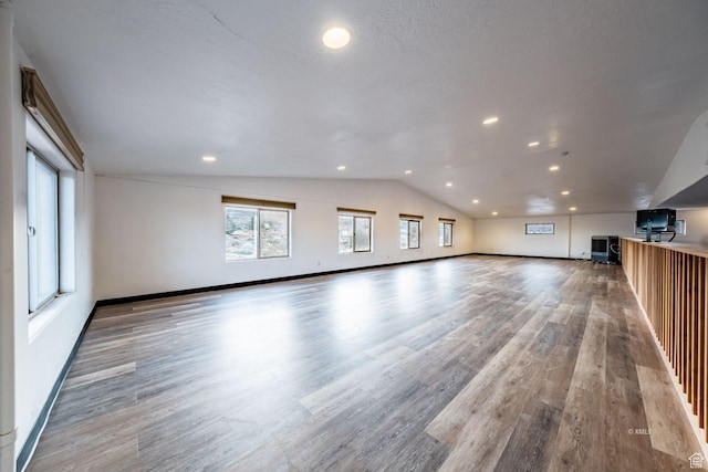 unfurnished living room featuring recessed lighting, vaulted ceiling, baseboards, and wood finished floors