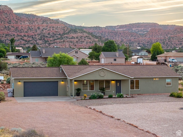 ranch-style house featuring a mountain view, driveway, an attached garage, and stucco siding