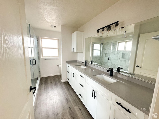 full bath with double vanity, visible vents, a sink, and wood finished floors