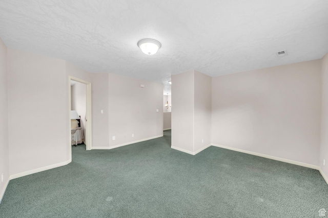 empty room featuring a textured ceiling, dark colored carpet, visible vents, and baseboards