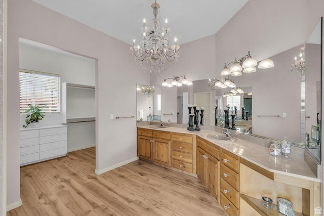 full bathroom featuring a sink, double vanity, a healthy amount of sunlight, a notable chandelier, and wood finished floors