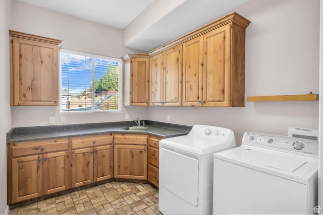 washroom with brick patterned floor, a sink, independent washer and dryer, and cabinet space