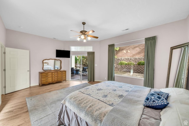bedroom with a ceiling fan, wood finished floors, baseboards, access to outside, and visible vents