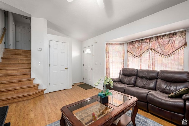 living room with lofted ceiling, light wood finished floors, and stairs