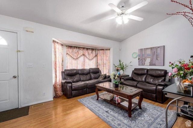 living room featuring vaulted ceiling, ceiling fan, visible vents, and light wood-style floors