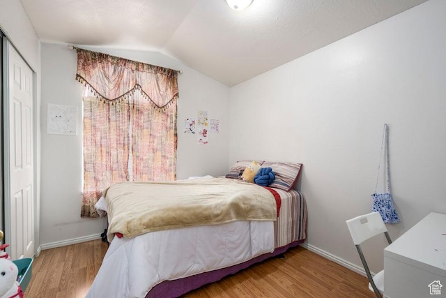 bedroom featuring baseboards, vaulted ceiling, and wood finished floors