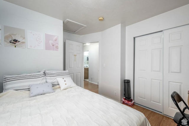 bedroom with attic access, a closet, and wood finished floors