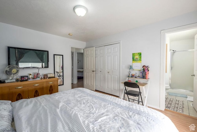 bedroom with ensuite bathroom, a closet, wood finished floors, and baseboards