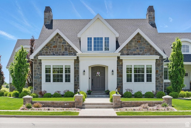 view of front of house with stone siding, a chimney, board and batten siding, and a front yard