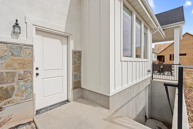 doorway to property with board and batten siding and a shingled roof
