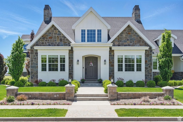 view of front of house featuring stone siding, board and batten siding, and a chimney